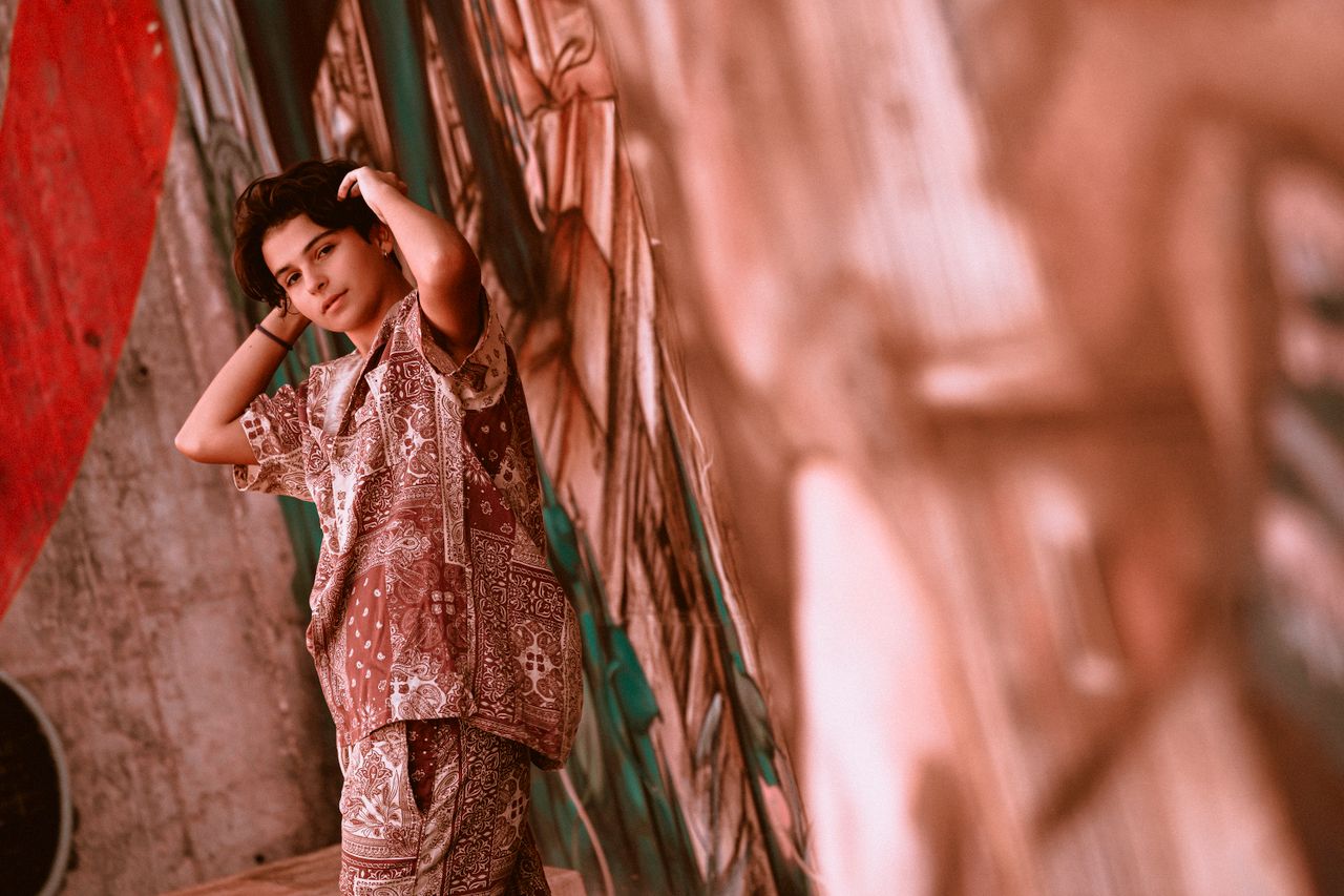 a trendy teenager poses against a colorful urban mural showcasing mode