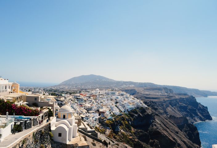 Scenic view of Santorini's iconic whitewashed buildings and coastal cliffs under a clear blue sky.