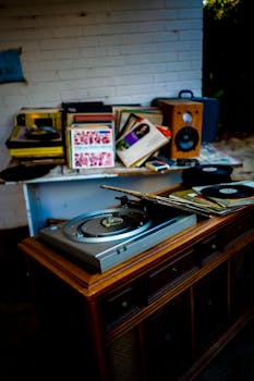 A nostalgic setup featuring a vintage record player surrounded by a collection of vinyl records and speakers.