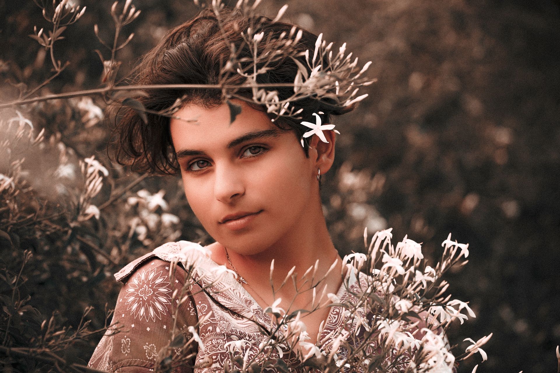 A young adult posing among jasmine flowers, showcasing a serene and natural beauty.