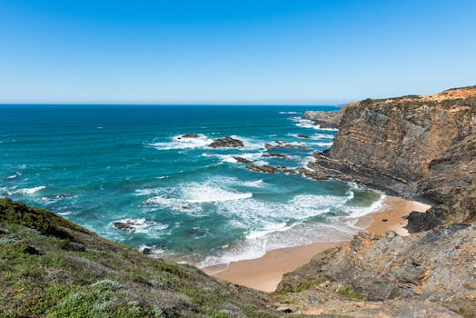 Breathtaking view of Portugal's rugged Alentejo coastline with dramatic cliffs and vibrant blue ocean.