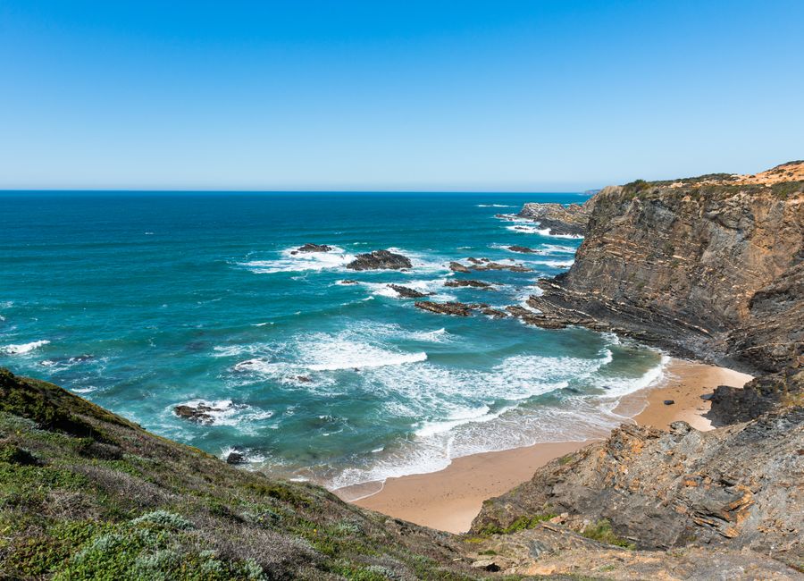 Breathtaking view of Portugal's rugged Alentejo coastline with dramatic cliffs and vibrant blue ocean.