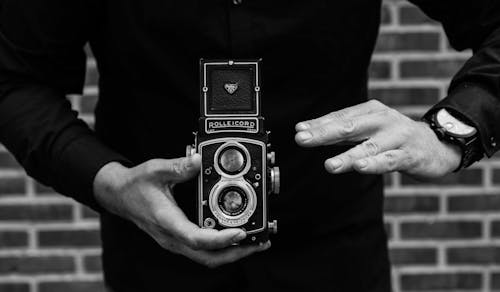 Grayscale Photography of Man Holding Rolleicord Camera