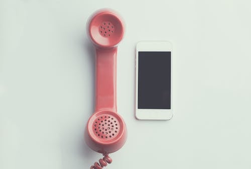 Flat Lay Photography of Red Anti-radiation Handset Telephone Beside Iphone