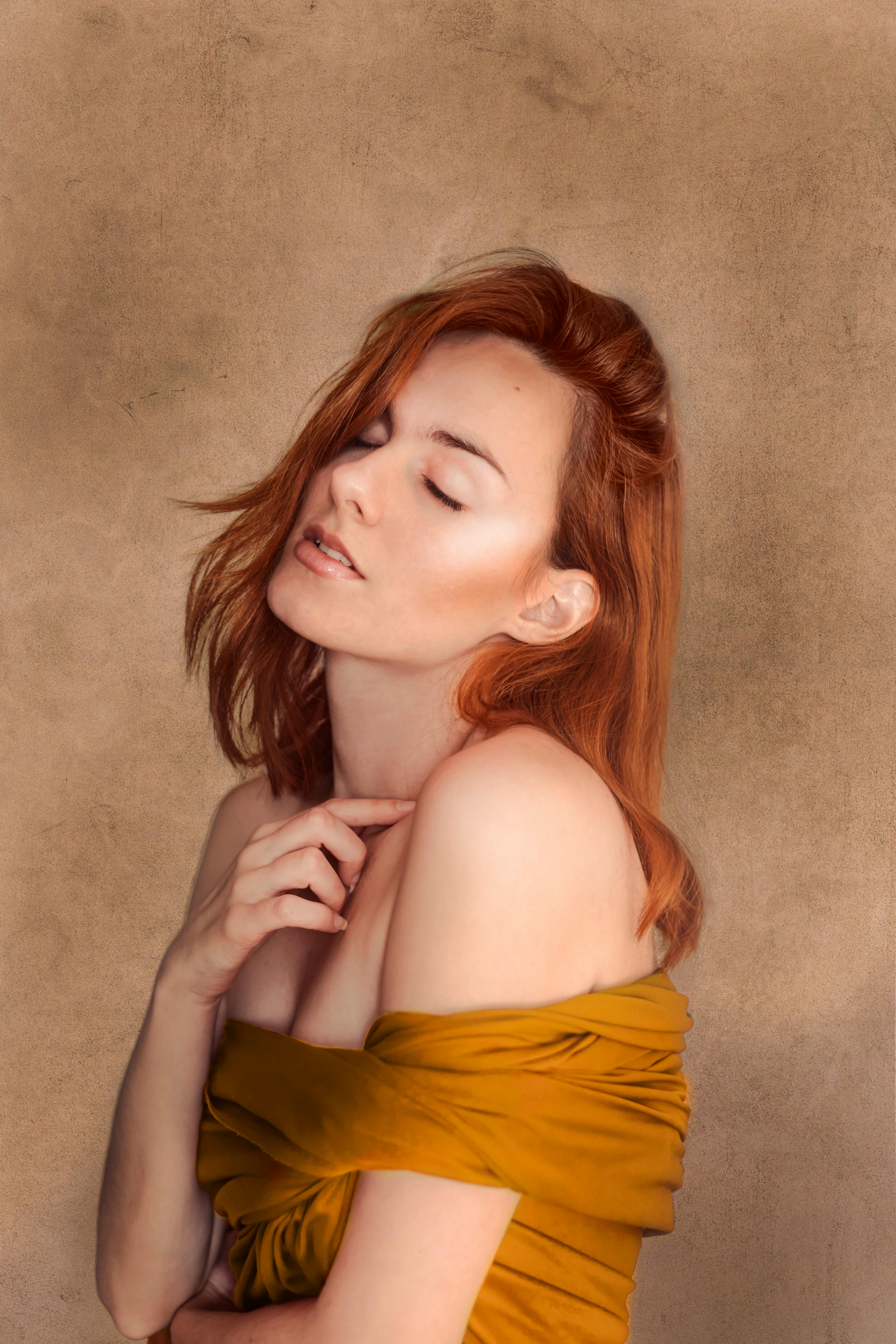 Artistic portrait of a redheaded woman posing gracefully in an off-shoulder outfit.