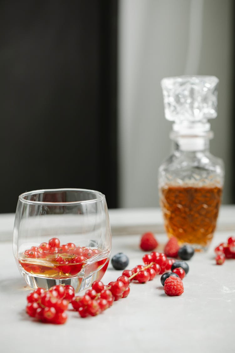 Glass Of Whiskey On Table With Berries