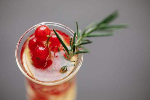Free High angle of transparent glass filled with champagne served with fresh red currant and rosemary Stock Photo
