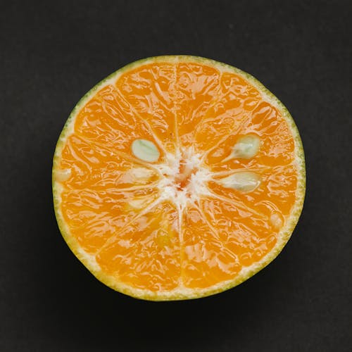 Top view of fresh healthy juicy slice of ripe orange placed on black background