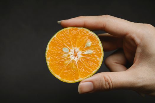 在黑色背景下，一位匿名女性展示富含维生素和大量元素的新鲜多汁水果，以促进健康生活