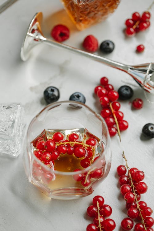 Free From above composition of glassware with whiskey and red currant placed on table near bottle wineglass and berries Stock Photo