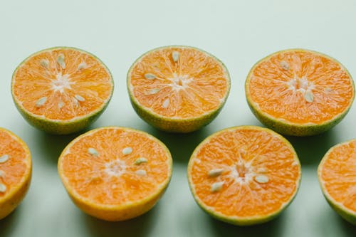 From above of fresh healthy appetizing healthy oranges cut in halves on green surface