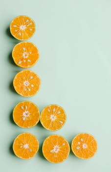 Fresh sliced oranges creatively arranged on a pastel green background for healthy eating concept.