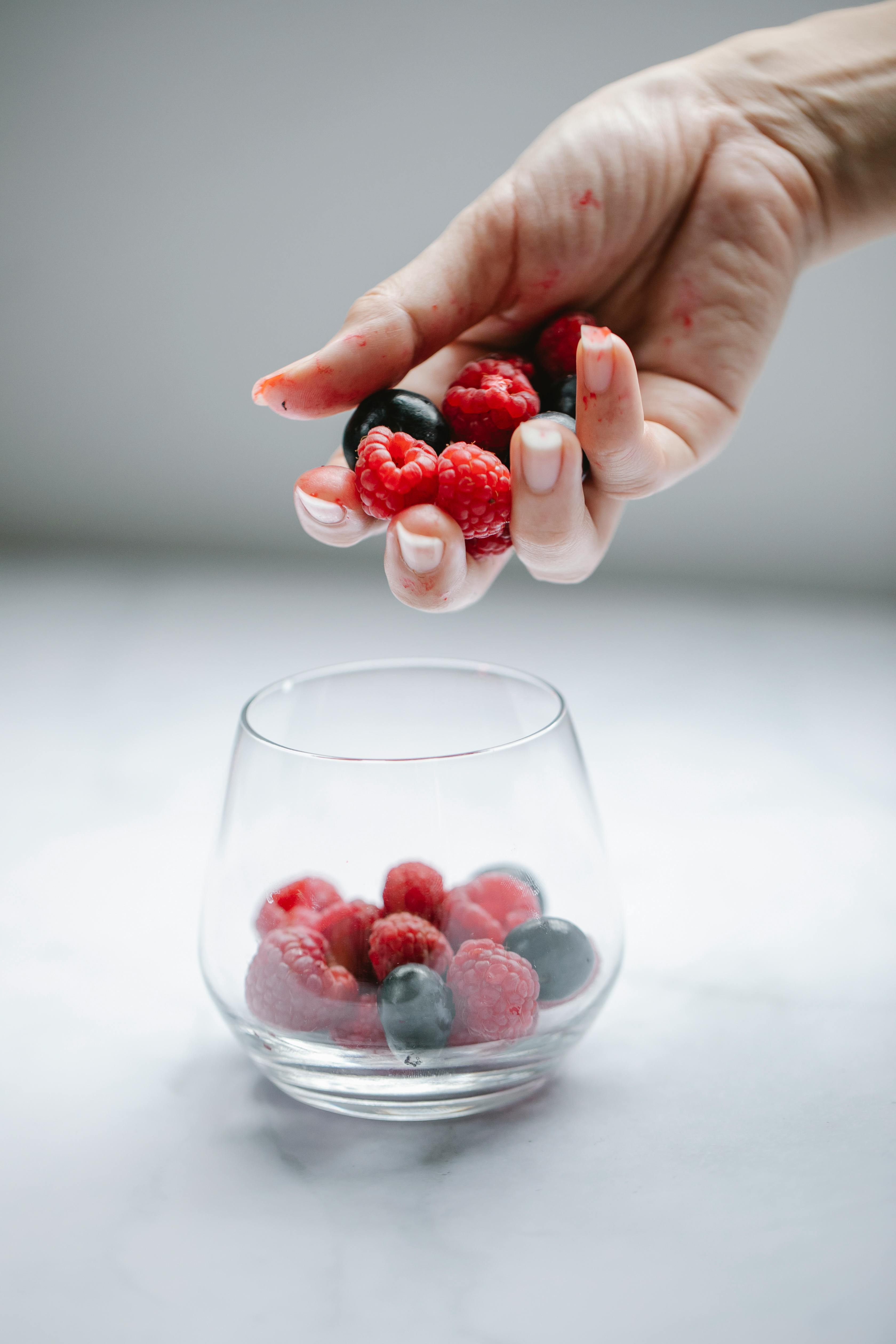 Woman putting berries into glass cup · Free Stock Photo