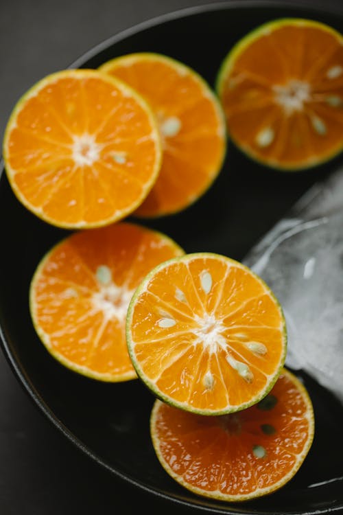 From above of sliced juicy orange in ceramic bowl with ice for vegetarian diet