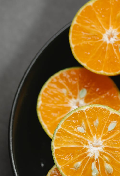 Free From above of appetizing tasty oranges in bowl for organic vitamin diet on gray table Stock Photo
