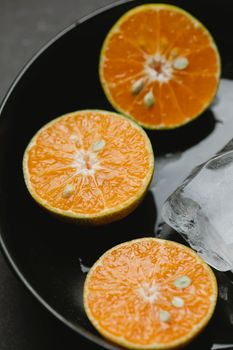 From above of fresh juicy cut orange placed near ice in ceramic bowl