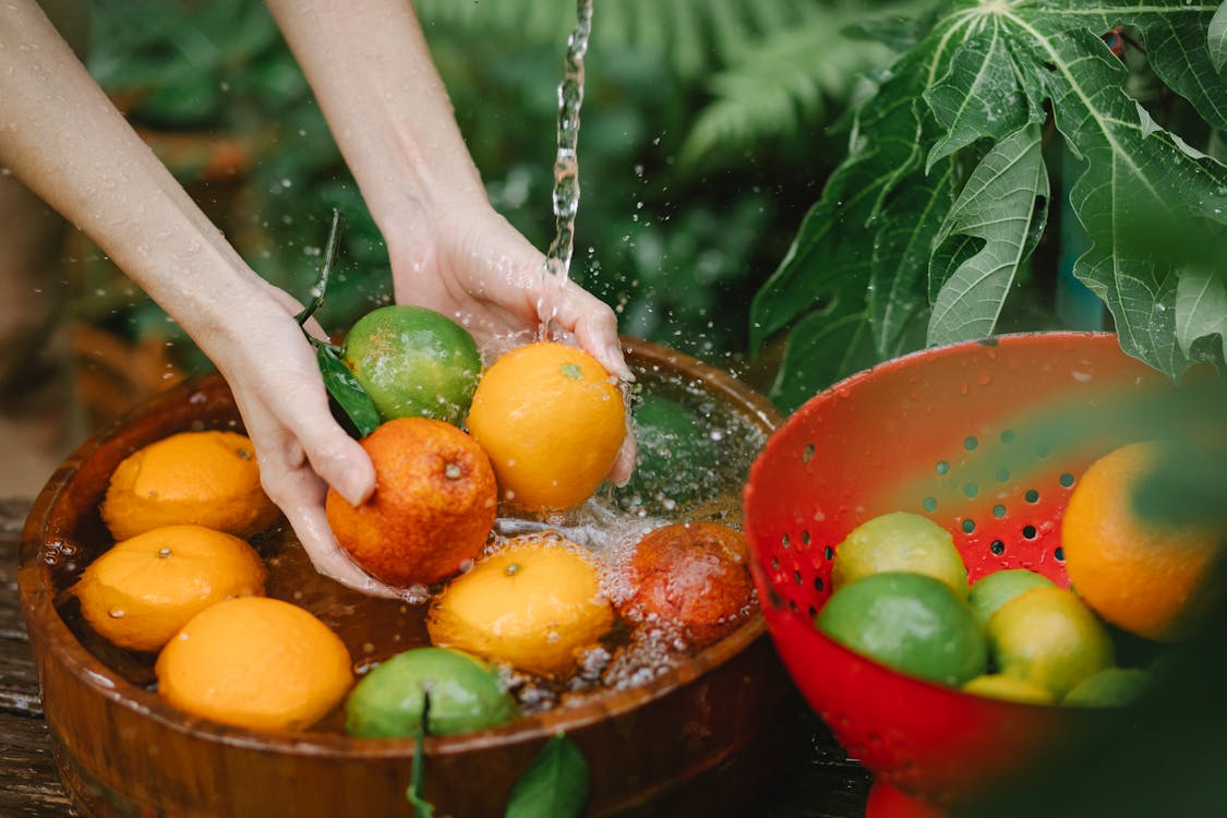 Woman washing fresh fruits in tropical orchard