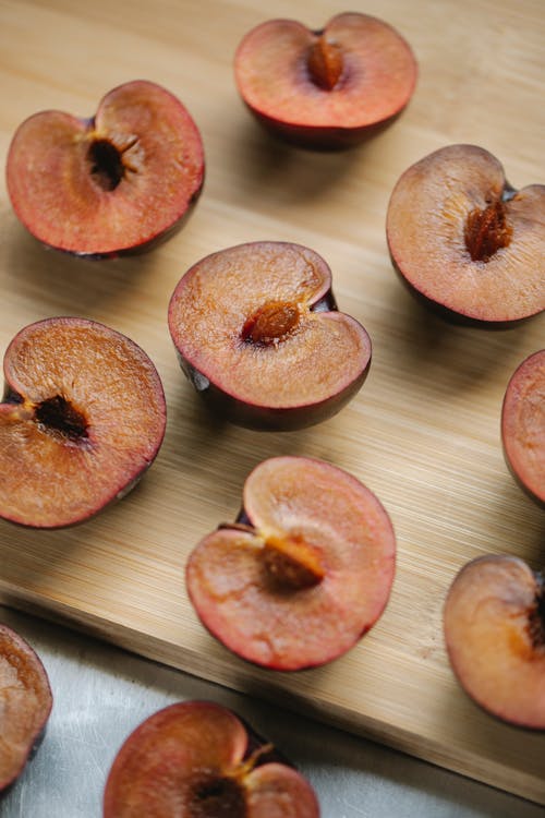 Juicy appetizing halved plums arranged on wooden board