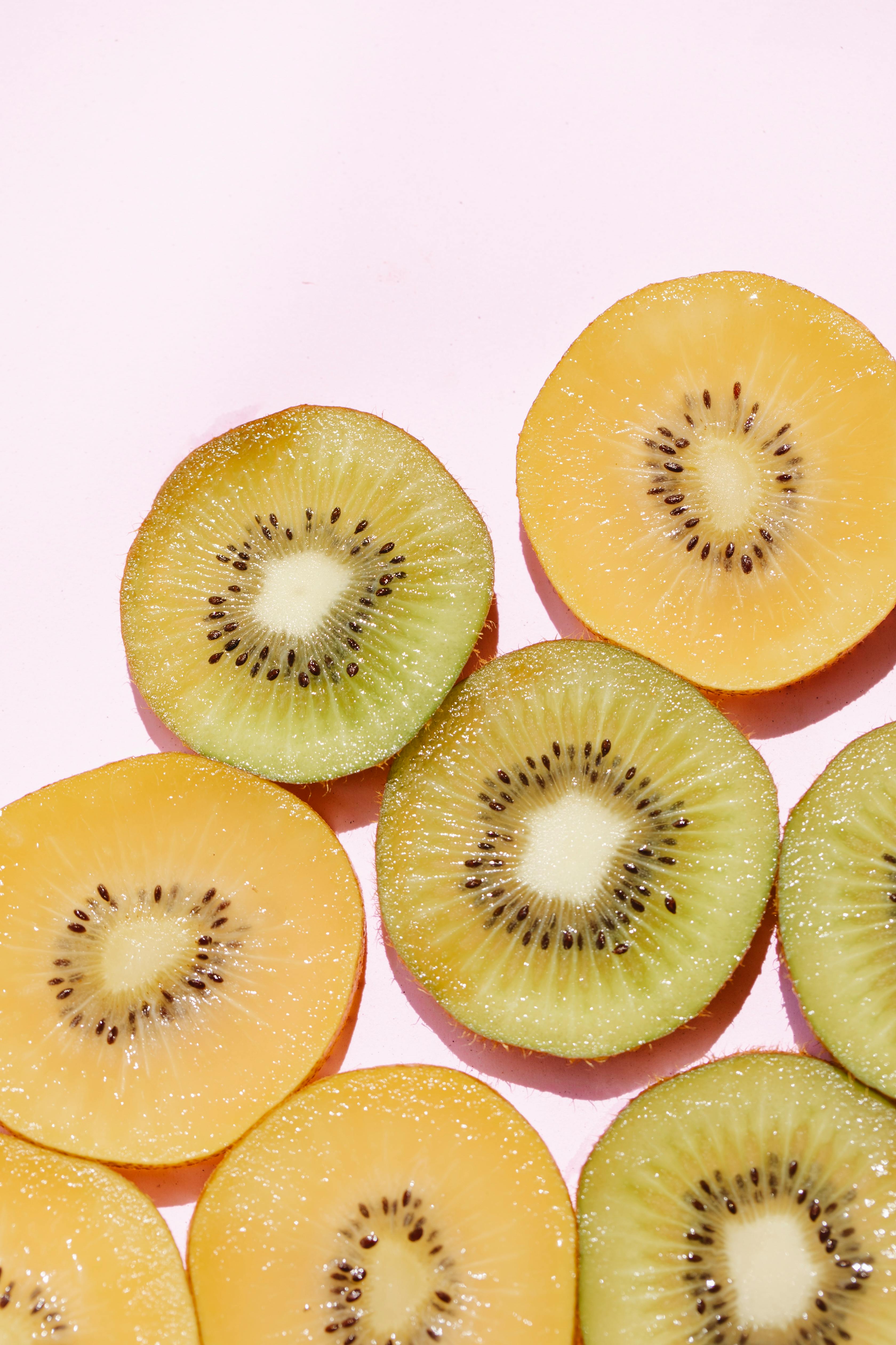 sliced assorted juicy kiwis on pink surface