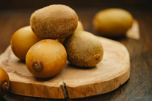 Heap of ripe fresh green kiwi placed on timber cutting board for healthy natural meal