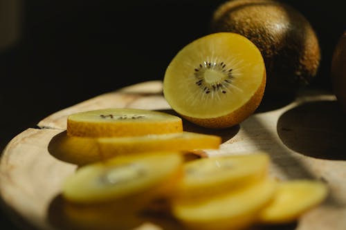 Cut fresh green kiwi with seeds on wooden cutting board in bright sunshine