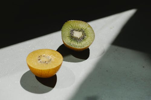 Sliced ripe green and yellow kiwi on table