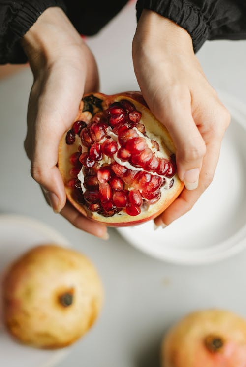 Woman having half of healthy ripe pomegranate