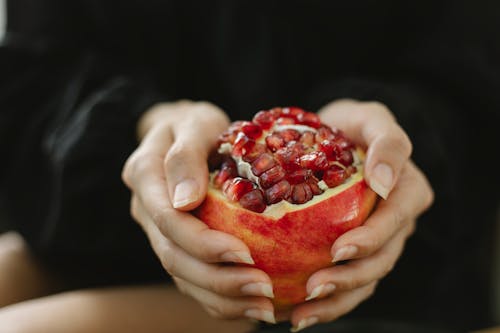 Frau, Die Reifen Granatapfel In Den Händen Zeigt