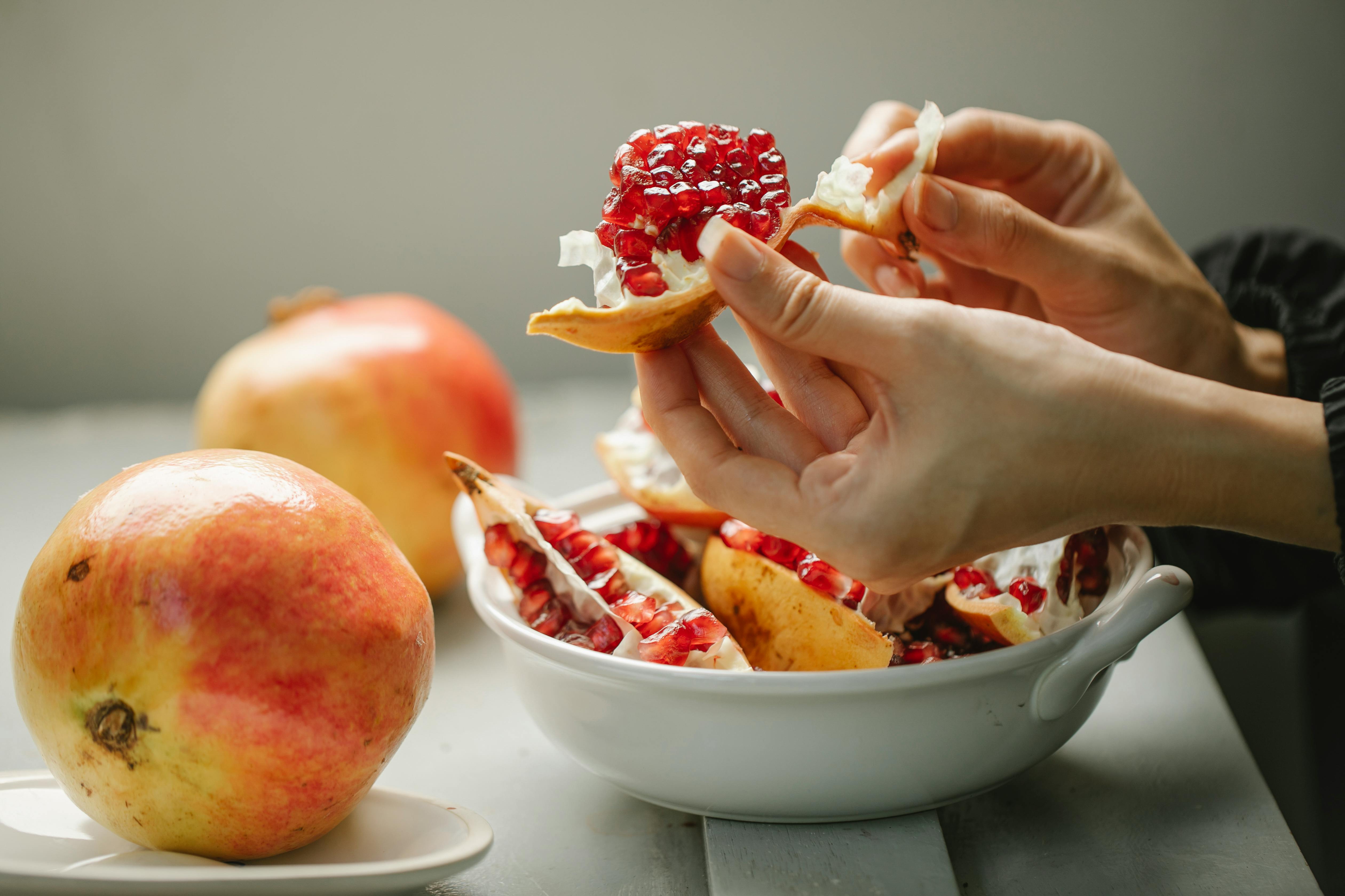 woman taking off peel from ripe pomegranate