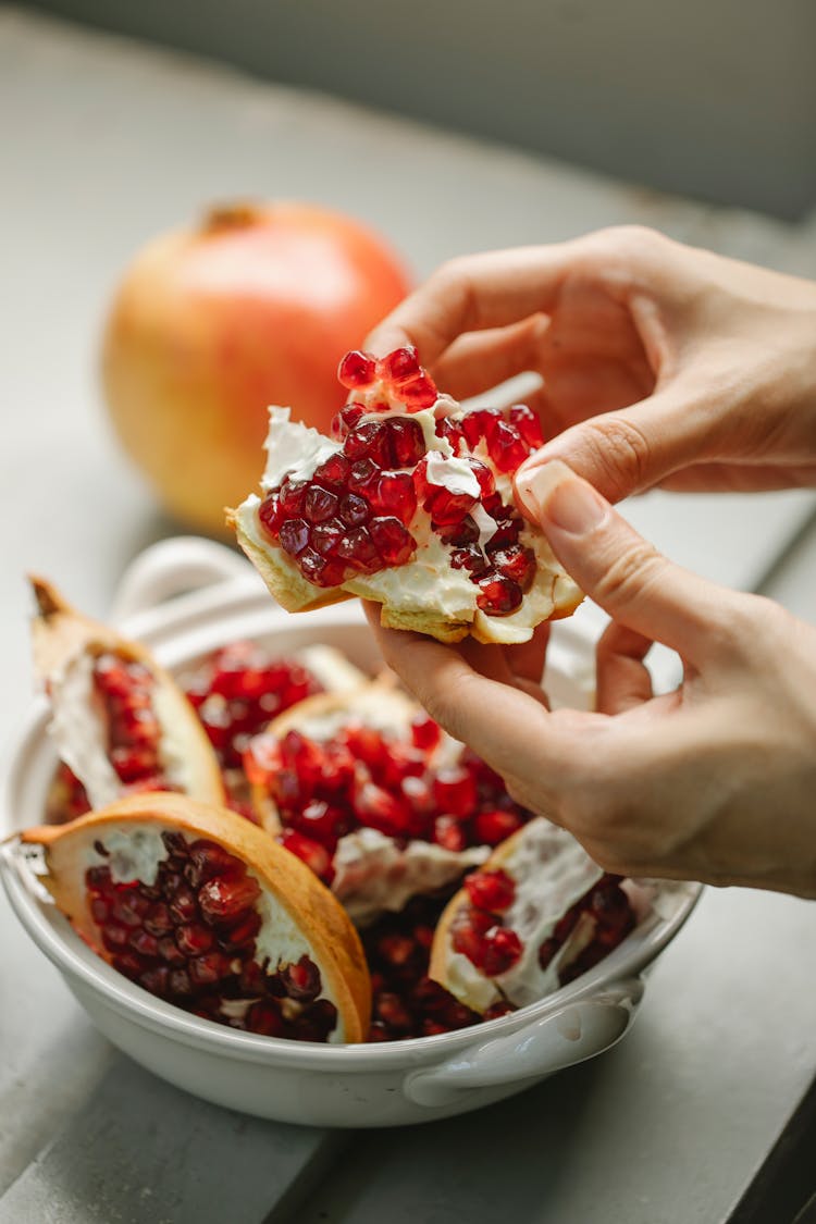 Crop Woman With Chunk Of Pomegranate In Hands