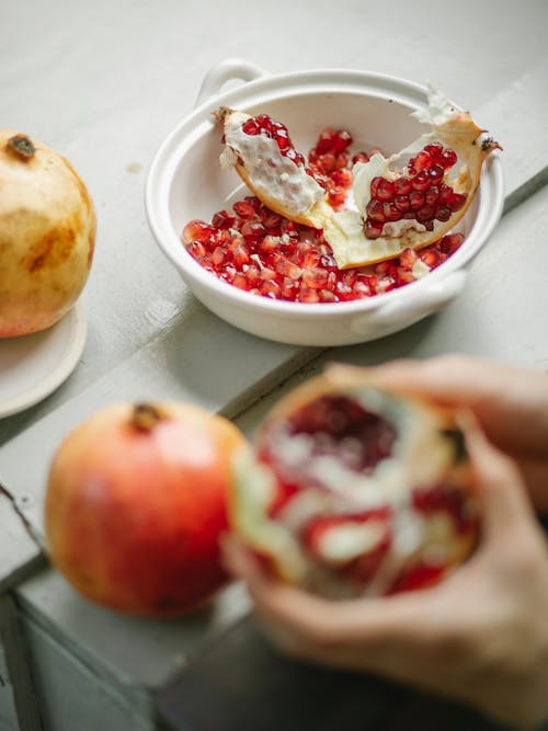 Crop person peeling pomegranate in kitchen