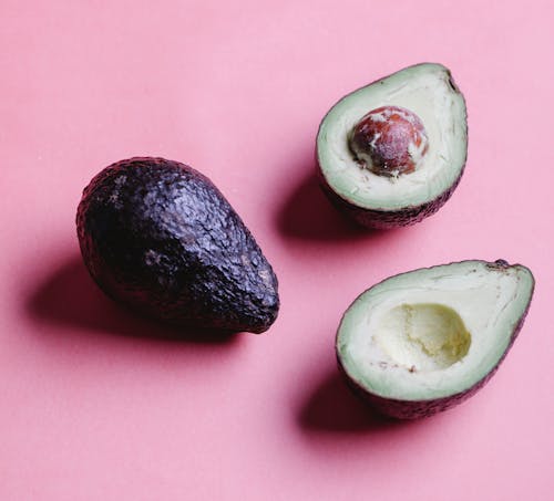 Composition of halved avocados on pink background