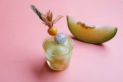 Glass of melon cocktail on pink background