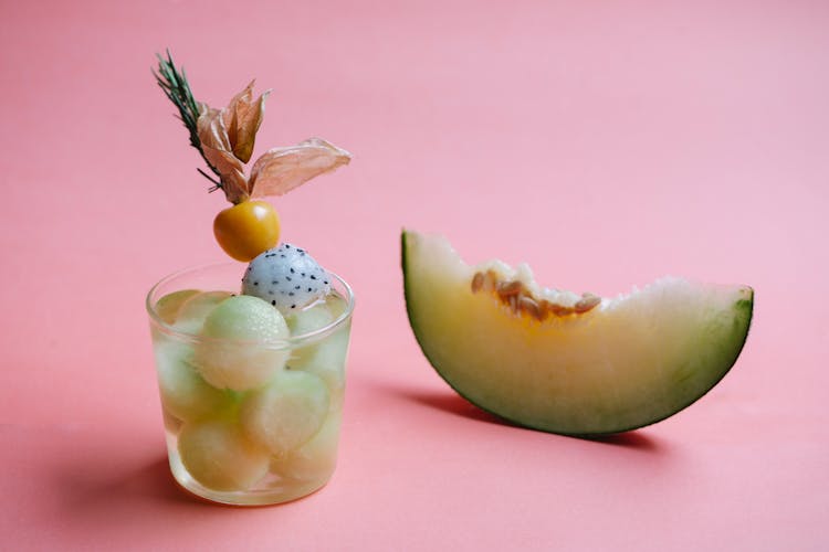 Glass Of Cocktail And Slice Of Melon On Background