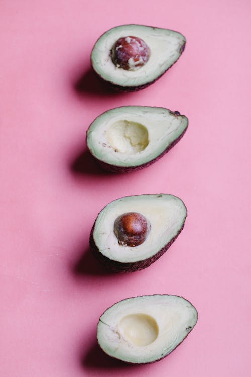 Rij Van Gehalveerde Avocado's Op Roze Achtergrond