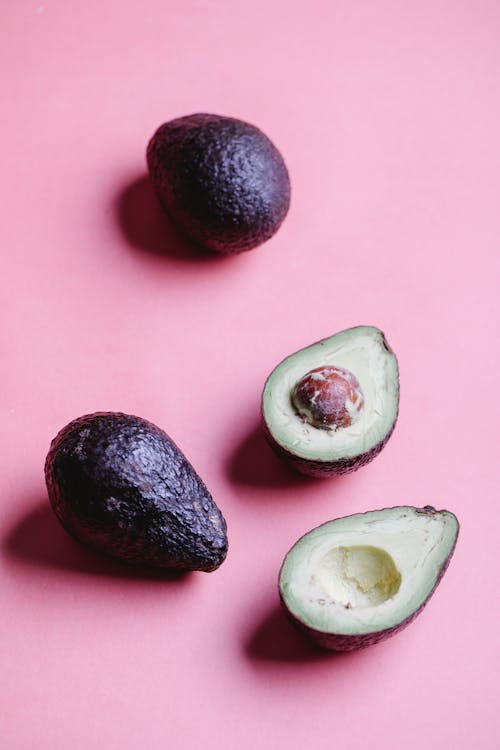 Ripe avocados on pink background