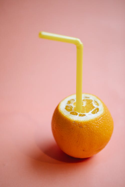 Cut juicy orange with straw