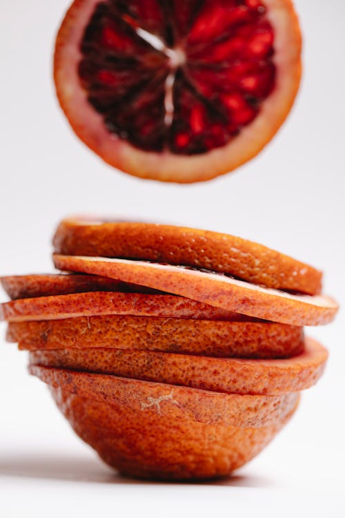 Free Heap of cut sliced unpeeled fresh ripe juicy red orange on white background Stock Photo