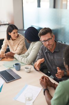 A diverse group of colleagues having an engaging discussion in a modern office setting.