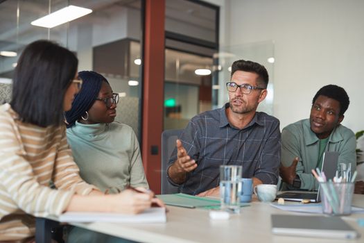 A diverse group of professionals having an animated discussion in a modern office setting.