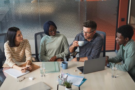 A diverse group of colleagues engaged in a discussion during a team meeting in a modern office.