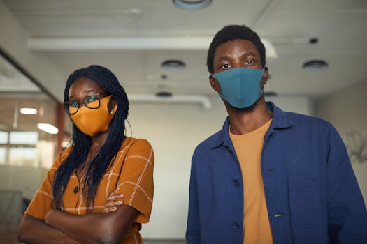 Two colleagues in an office setting wearing colorful face masks, showcasing safety measures.