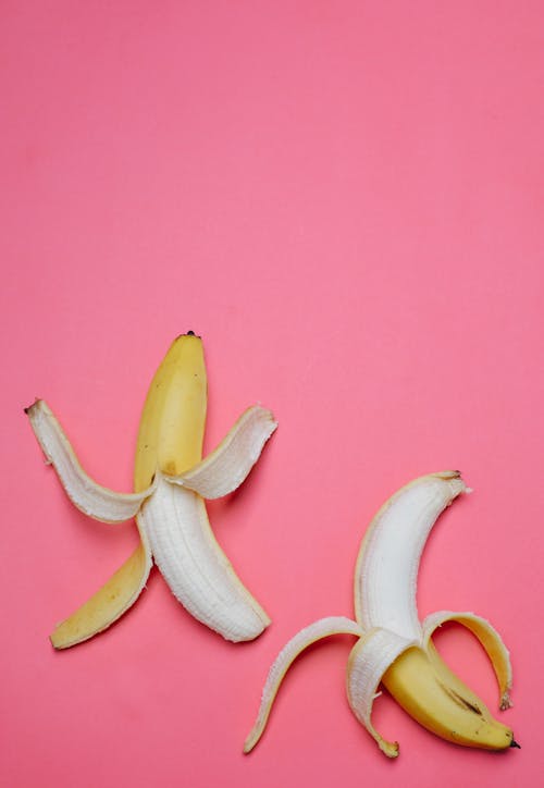 Peeled bananas on pink background