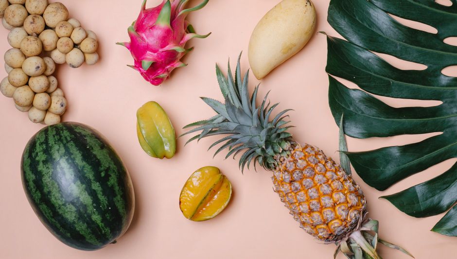 Photo by Any Lane Top view of different fresh ripe exotic fruits with big green tropical leaf on beige background