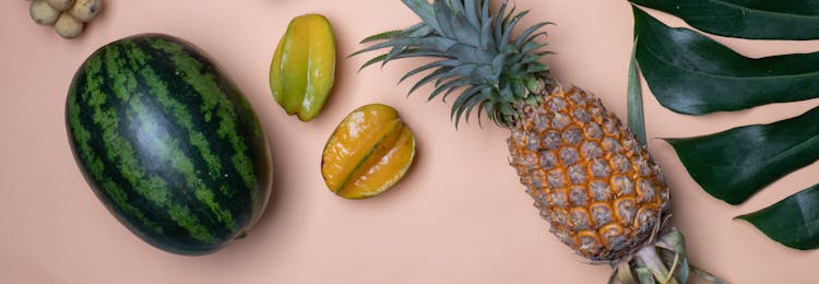 Pineapple And Carambolas Placed Near Watermelon And Palm Leaf