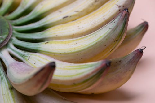 Bunch of fresh small bananas with dark spots located on pink surface
