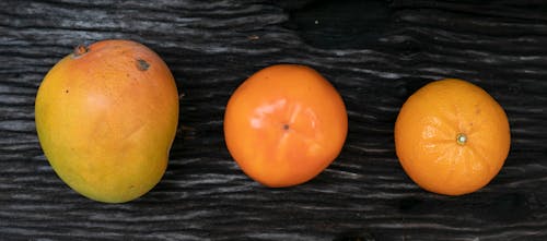 Composition of fresh ripe orange mandarin and persimmon placed near mango