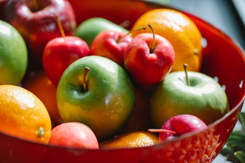 Delicious multicolored apples and oranges with mandarins located in red bowl