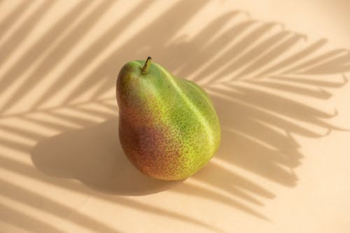 Fresh organic fruit pear located against white surface in sunbeam