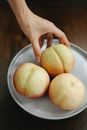 From above of unrecognizable woman taking fresh ripe sweet peach from white plate